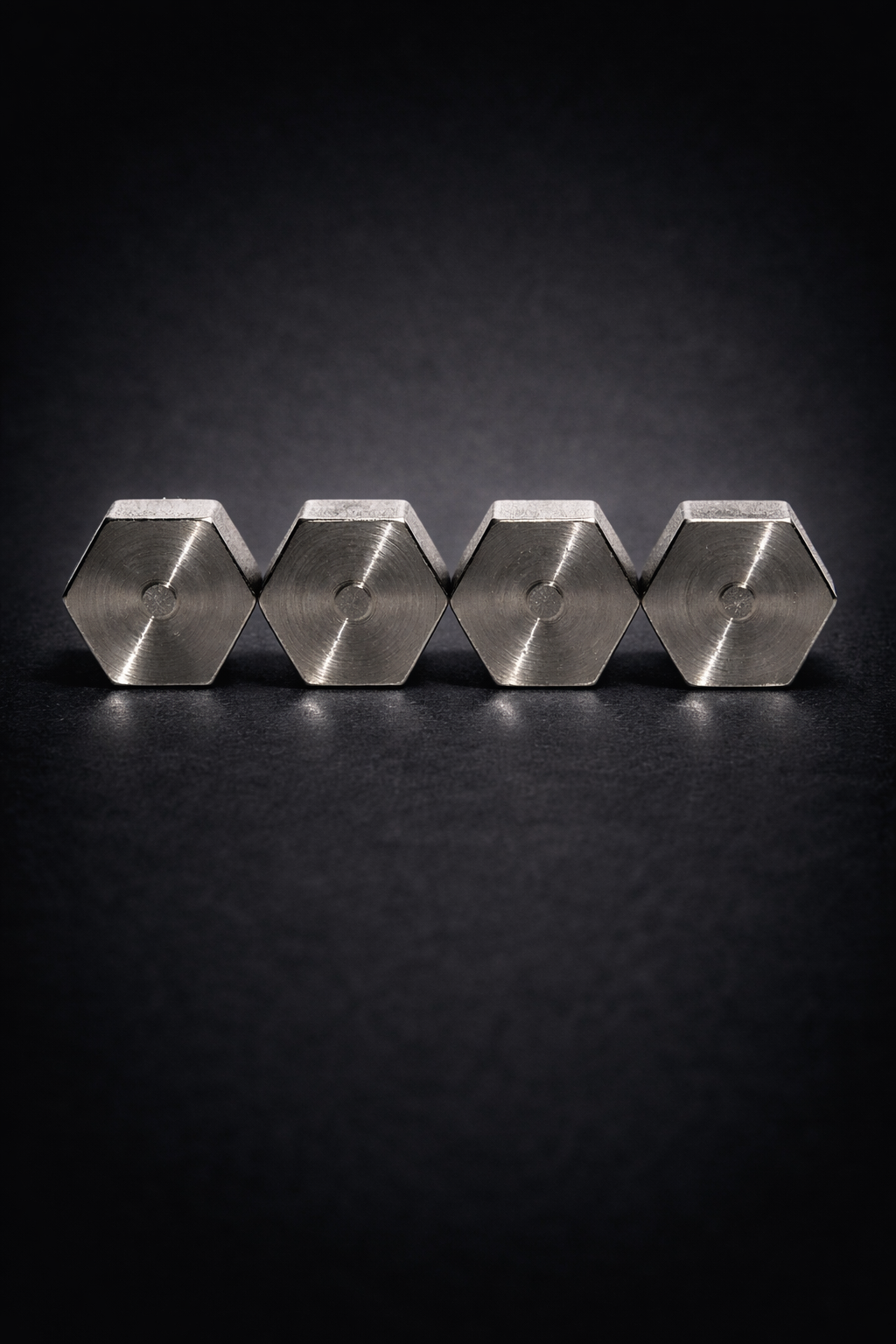Four stainless steel Dognuts viewed from the capped face on a dark surface.